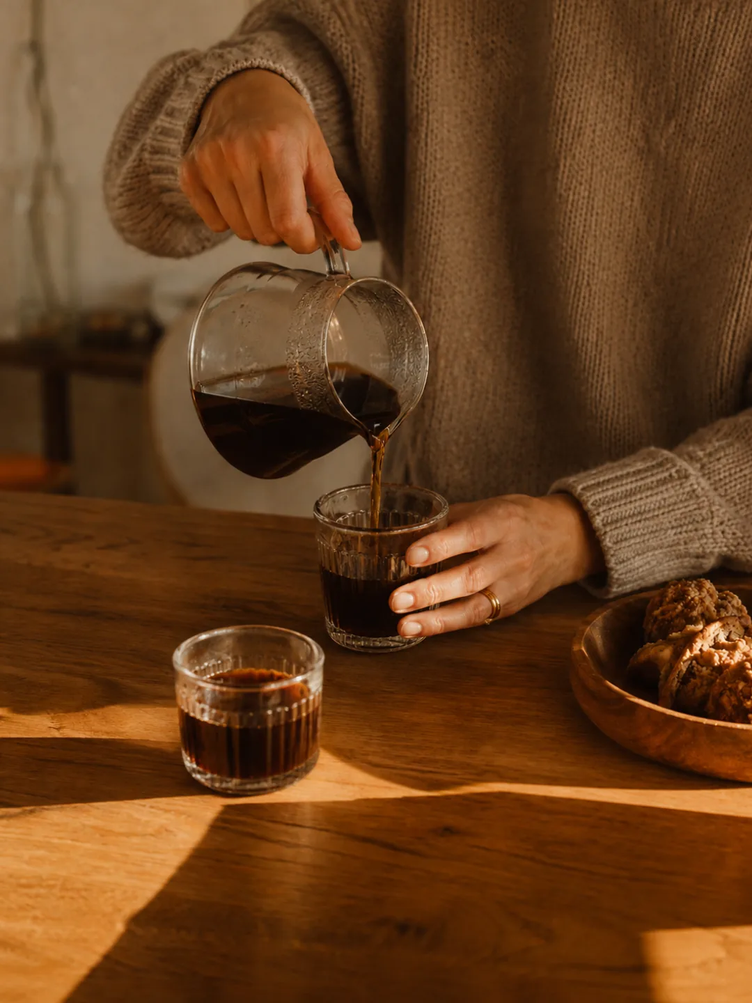 Filter coffee poured into a ribbed glass on a sunlit timber table